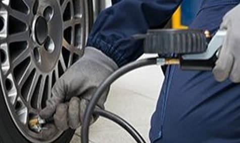 Mechanic checking tire pressure with an air gauge